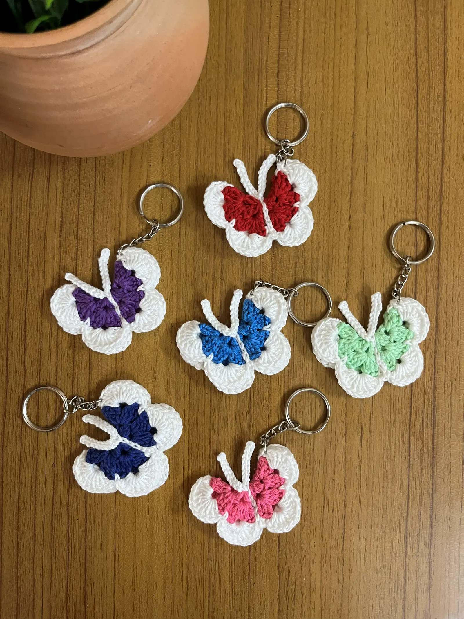Set of colorful butterfly crochet keychains on a wooden surface